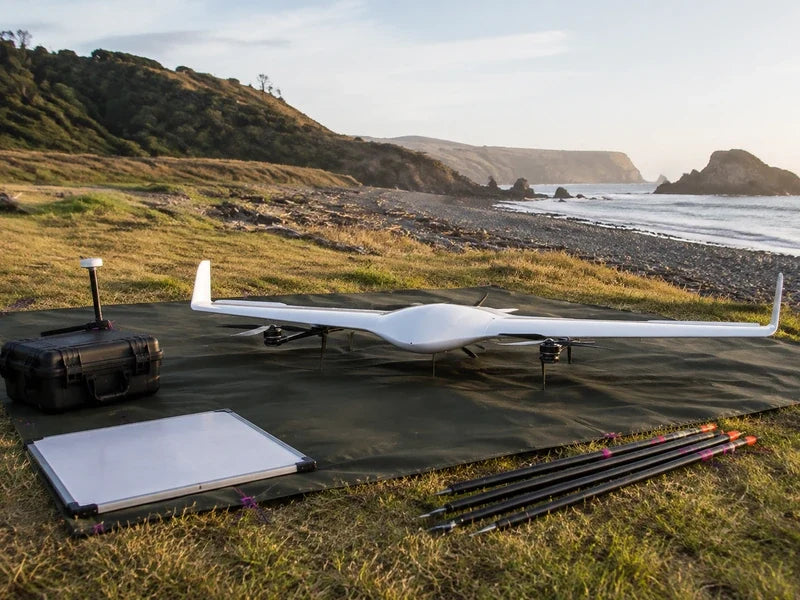 Complete UG21 fixed-wing VTOL at a coastal mapping staging area with survey equipment