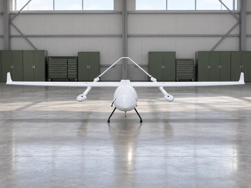 UG62 in exact frontal view parked on its reference landing supports on a clean indoor hangar floor, distant green instrument storage cabinets