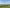 UG25 in its exact front-left reference orientation above an empty patchwork of nursery and meadow parcels, bright natural light, subtle magenta field marker