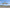 UVH1 in the exact underside reference attitude above an empty gravel survey staging strip with pale green hills beyond, full aircraft visible.