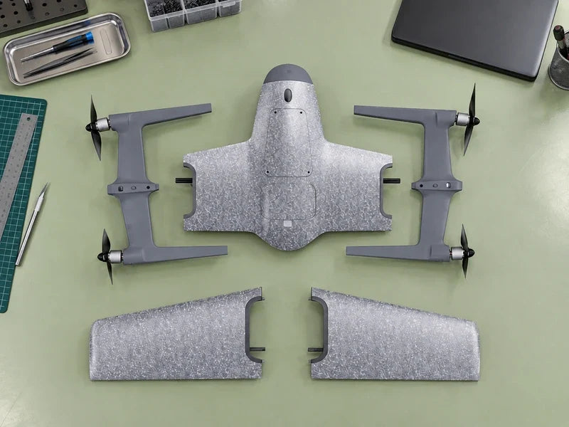 UVH-PNP five unassembled gray foam component groups exactly as main reference arranged overhead on a clean pale green integration bench, closed dark laptop outside the component layout at upper right.