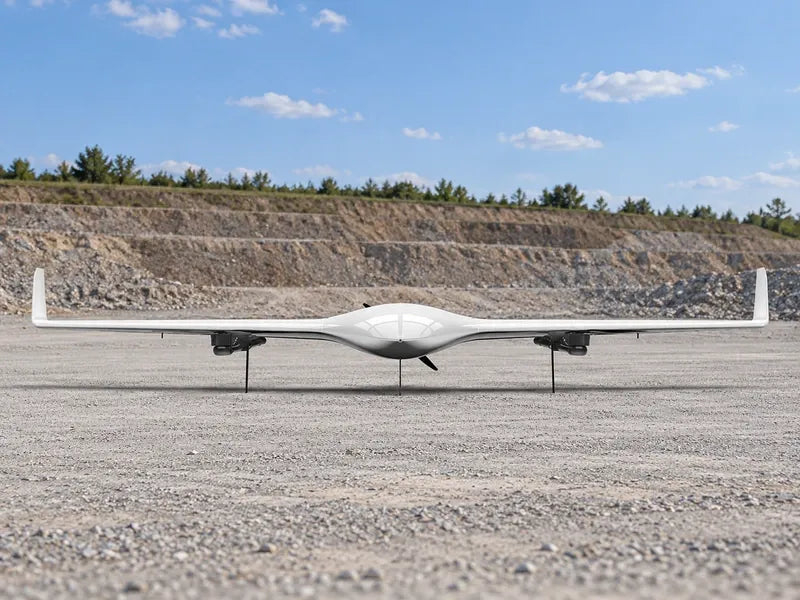 UG21 front-level full-span view resting on its original thin legs at the edge of an empty light-gray earthwork survey staging apron; distant stepped earth embankment, clear daylight, no people.