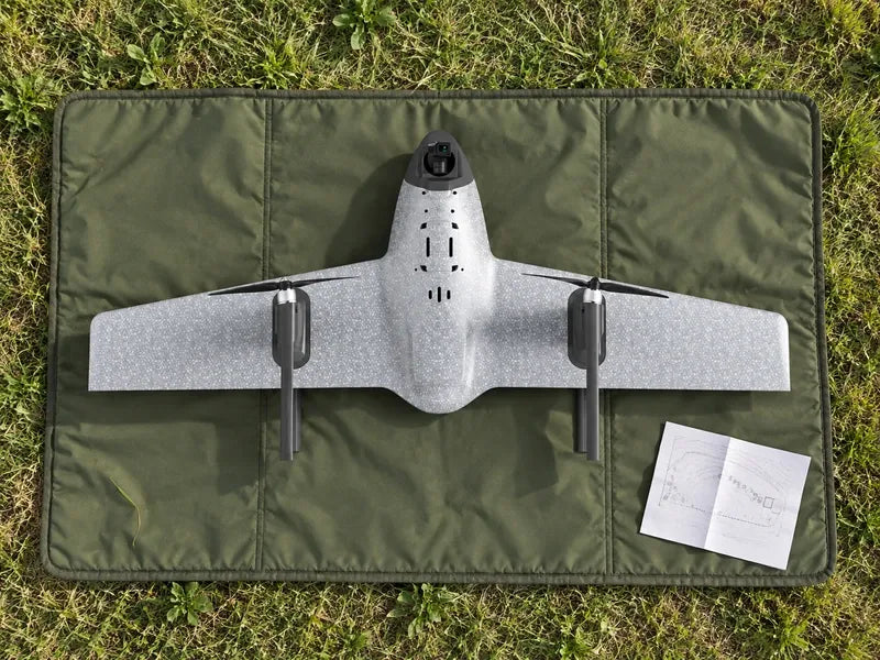 UVH1 viewed directly from above on a dark green field packing mat beside a folded boundary sketch